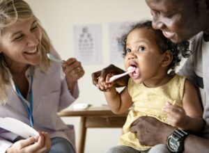dentist teaching a child how to brush their teeth